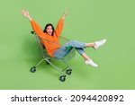 Small photo of Portrait of attractive cheerful childish foolish girl riding cart having fun good mood isolated over bright green color background