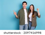 Photo of crazy lady guy celebrate luck lottery win ads indicate point hand empty space fists up isolated on blue color background