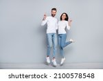 Full size photo of funny millennial brunet couple jump wear white shirt jeans sneakers isolated on grey background