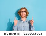 Portrait of excited cheerful man look indicate fingers up empty space proposition isolated on blue color background