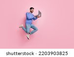 Small photo of Full length photo of funny pretty guy dressed blue pullover jumping high typing modern device isolated pink color background