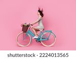 Profile side full body photo of positive cheerful lady wear mini skirt ride bicycle weekend look empty space isolated on pink background