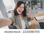 Small photo of Portrait of positive pretty girl sit chair take selfie record video eye wink pointing finger you workplace indoors