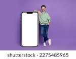 Small photo of Full body photo of attractive young man leaning vertical white banner gadget dressed stylish khaki look isolated on purple color background