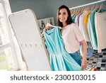 Photo of charming pretty young girl wear pink t-shirt trying on new teal dress looking mirror indoors home room