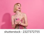 Photo of funny gorgeous pretty woman wear colorful dress hold smartphone look empty space laughing isolated on pink color background