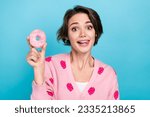 Photo of cute positive lady bite tongue lick lips teeth hand hold glazed donut isolated on blue color background