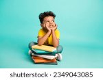 Small photo of Full body photo of cute little boy look empty space lean on books pile wear trendy yellow clothes isolated on aquamarine color background