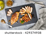 Grilled chicken fillets on slate plate. Gray concrete background