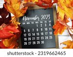 Small photo of November 2023 monthly calendar with maple leaf on wooden background