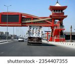Small photo of Cairo, Egypt, August 21 2023: Shinzo Abe axis patrol highway in Egypt with a pedestrian bridge in traditional Japanese architectural style, flatbed truck big vehicle with a shipment container on it