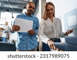 Small photo of Two employees using new modern printer in office