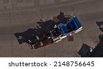 Small photo of Aerial view of a single fiacre coach with two horses driving on a paved road in the historic center of city Vienna, Austria on sunny day with the carriage's shadow on the ground.