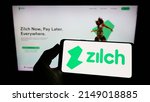Small photo of Stuttgart, Germany - 03-30-2022: Person holding mobile phone with logo of fintech Zilch Technology Limited (PayZilch) on screen in front of web page. Focus on phone display. Unmodified photo.
