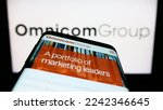 Small photo of Stuttgart, Germany - 12-10-2022: Mobile phone with webpage of US media company Omnicom Group Inc. on screen in front of business logo. Focus on top-left of phone display. Unmodified photo.