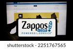 Small photo of Stuttgart, Germany - 01-13-2023: Person holding cellphone with logo of US online shop company Zappos.com LLC on screen in front of business webpage. Focus on phone display. Unmodified photo.