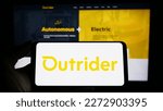Small photo of Stuttgart, Germany - 03-07-2023: Person holding mobile phone with logo of American company Outrider Technologies Inc. on screen in front of web page. Focus on phone display. Unmodified photo.