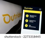 Small photo of Stuttgart, Germany - 03-07-2023: Person holding cellphone with webpage of US company Outrider Technologies Inc. on screen in front of logo. Focus on center of phone display. Unmodified photo.
