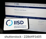 Small photo of Stuttgart, Germany - 04-01-2023: Person holding cellphone with logo of think tank IISD institute on screen in front of webpage. Focus on phone display. Unmodified photo.