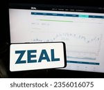 Small photo of Stuttgart, Germany - 08-24-2023: Person holding mobile phone with logo of German lottery company ZEAL Network SE on screen in front of business web page. Focus on phone display. Unmodified photo.