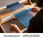 Small photo of Woman is weaving a weft thread between the warp threads, Single shuttle loom