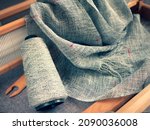 Small photo of Weaving fabric on hand loom machine. Textile industry. Gray linen woven cloth, shuttle, reed and bobbin of yarn