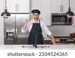 Small photo of Chef cook with ok sign, delicious food. Portrait of chef man in a chef cap in the kitchen. Man wearing apron and chefs uniform and chefs hat. Character kitchener, chef for advertising.