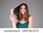 Small photo of Studio portrait of attractive pretty haired girl combing hair. Hair care, hairs salon. Beautiful woman with healthy skin straight hair isolated on studio background. Hairs day. Beautiful smooth hair.
