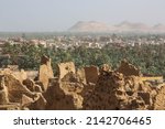 Small photo of View of Shali Fortress ruins in old town, palm trees in oasis and sandy hills in the background. Siwa oasis in Egypt.