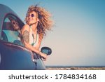 Attractive curly blonde young woman smile and enjoy the wind outside the car - concept of beauty and travel for happy and cheerful caucasian people - alternative lifestyle female feel the freedom joy