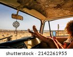 Interior of classic van camper with beautiful legs of woman stretched and relaxed. Travel people lifestyle concept. Summer holiday vacation and vanlife. Dreamcatcher and beach view holiday vacation