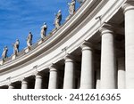 Small photo of Architectural columns with carved statues of saints and other Christan religious figures against a clear blue sky