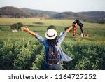 Asian woman traveler with backpack holding camera and looking at amazing mountains and forest, travel holiday relaxation concept.