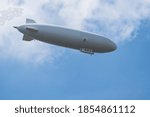 Airship flying in blue sky under white clouds