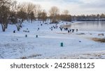 Small photo of Winter tumult with sleds on a snowy slope by frozen lake on a day off