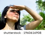 Small photo of Asian woman having problem sunburn redness on face skin hand cover her face to protect ultraviolet from sunlight standing outdoors under sunny