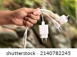 Small photo of Close up photo of man holding multiple unplugged charging sockets. Concept of energy saving and reduce electricity usage.