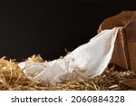 Small photo of Wood manger or cradle with white linen and hay with a black background with copy space