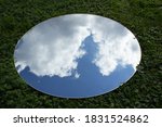 Photo of a mirror on green grass you can clearly see the blue sky
