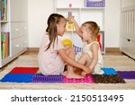 Small photo of Girls play and have fun together in the children's room on the floor on orthopedic massage mats. Droll kids playing and laughing