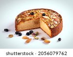 Small photo of Cake. Mawa Cake is a rich, delicious cake made with mawa and atta. Isolated on white background with dry fruit nuts. Homemade round half cut sponge cake. Almond, Cashew, Blackberry, Pistachio.