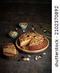 Small photo of Cake Mawa slice. Mawa cake is a rich, delicious cake made with mawa and atta. serve on wood background with dry fruit nuts. Homemade round half cut sponge cake. Almond, Cashew, Blackberry, Pistachio.