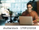 Small photo of Businessman working online with a laptop while sitting at his desk in an office after hours