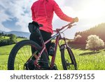 Small photo of Woman cyclist with a mountain bike in a grass landscape. Visible logos and names was retouched or changed beyond recognition.