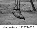 Small photo of Ruined seats of an old abandoned swing. Black and white photo of an old abandoned playground. Melancholy childhood memories. Seats hung with chains ruined by time.