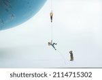 climbers pull themselves up on a rope to a globe