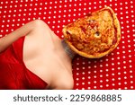 Small photo of Weird people concept. Young girl lying on table with pizza on her face over red-white background. Vintage, retro style. Complementary colors. Food pop art photography, fashion, kitsch concept