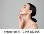 Small photo of Double chin treatment. Beautiful mature woman touching skin on neck over light grey background. Copy space for ad. Concept of fashion, beauty, spa, cosmetology, skin care, procedures.