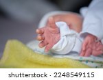 The newborn baby's hand reaches out as if trying to hold something