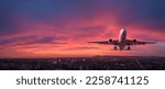 Small photo of Airplane is flying in colorful sky over the city at night. Landscape with passenger airplane, skyline, purple sky with red and pink clouds. Aircraft is landing at sunset. Aerial view. Transport